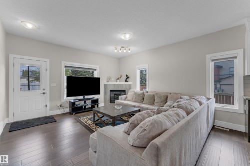Spacious living area featuring wood-finish flooring, light grey wall paint, and recessed lighting - 4506 49 Avenue, Beaumont, AB - Indoor Photo Showing Living Room With Fireplace