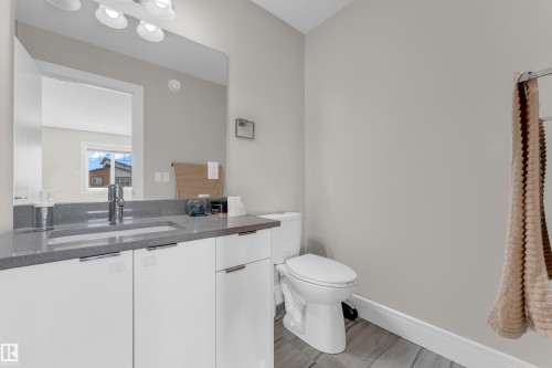Bathroom featuring a modern vanity with an integrated sink, polished chrome faucet, and quartz-finish countertop - 4506 49 Avenue, Beaumont, AB - Indoor Photo Showing Bathroom