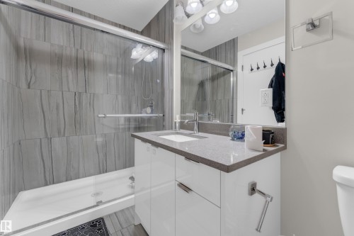 Bathroom featuring a modern vanity with a rectangular undermount sink, a gray speckled countertop, and a chrome single-handle faucet - 4506 49 Avenue, Beaumont, AB - Indoor Photo Showing Bathroom