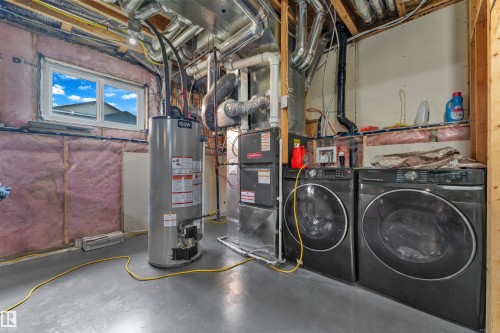 Utility area featuring a water heater, furnace, and a side-by-side washer and dryer - 4506 49 Avenue, Beaumont, AB - Indoor Photo Showing Laundry Room
