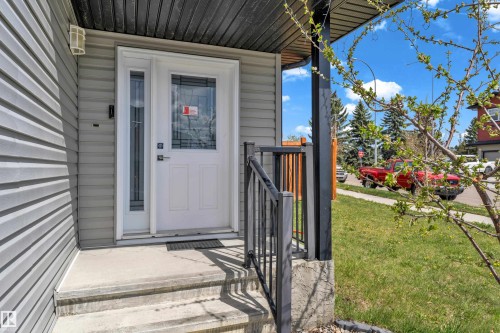 Inviting entryway featuring a white paneled door with decorative glass inserts, a single sidelight, and a concrete porch with steps - 4506 49 Avenue, Beaumont, AB - Outdoor With Deck Patio Veranda