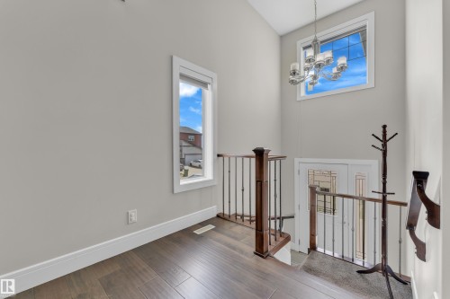 Two-story entryway featuring high ceilings, wood-finish flooring, and a decorative chandelier - 4506 49 Avenue, Beaumont, AB - Indoor Photo Showing Other Room
