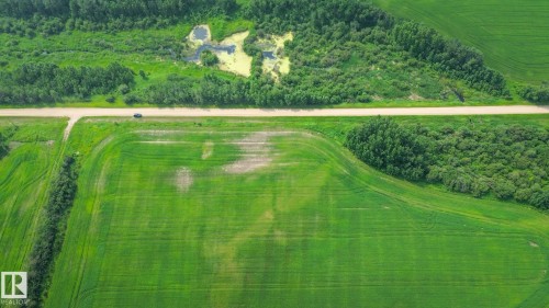 Expansive agricultural land featuring a verdant field, adjacent wooded areas, and a visible roadway - Sw-28-56-10 -W4, Rural St. Paul County, AB 