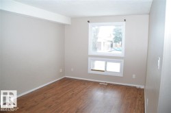 Spacious room featuring wood-finish flooring and a neutral color palette - 