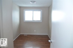 Room featuring wood-finish flooring, a white trim baseboard, and light-toned painted walls - 
