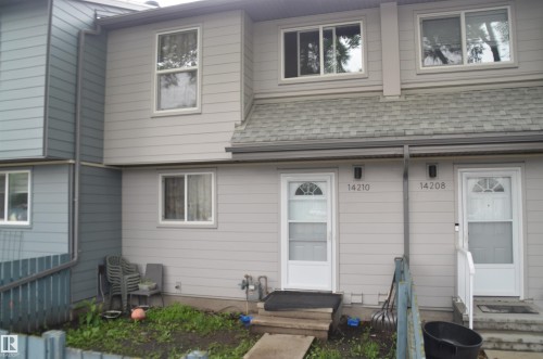 Duplex exterior featuring light gray horizontal siding, white-framed windows, and two distinct entrances with white storm doors - 14210 31 Street Nw, Edmonton, AB - Outdoor