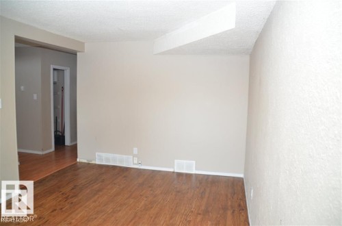 Spacious interior with wood-finish flooring, neutral-toned walls, and a textured ceiling - 14210 31 Street Nw, Edmonton, AB - Indoor Photo Showing Other Room