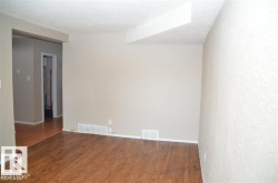 Spacious interior with wood-finish flooring, neutral-toned walls, and a textured ceiling - 