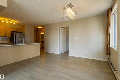 Kitchen with wood-finish cabinetry, stainless steel refrigerator, and breakfast bar - #1501 10180 104 St Nw, Edmonton, AB - Indoor Photo Showing Kitchen