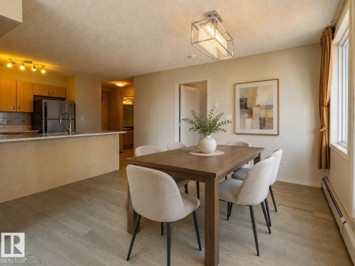 Spacious dining area featuring wood-finish flooring, a contemporary chandelier, and ample natural light - #1501 10180 104 St Nw, Edmonton, AB - Indoor Photo Showing Dining Room