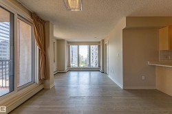 Bright living area featuring expansive windows, wood-finish flooring, neutral wall tones, and a built-in breakfast bar with tiled backsplash - 