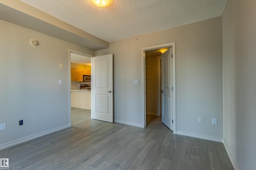 Room featuring light gray wood-finish flooring, neutral painted walls, and white trim - #1501 10180 104 St Nw, Edmonton, AB - Indoor Photo Showing Other Room
