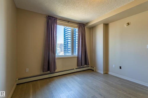 Bright interior space featuring light-toned wood-finish flooring, neutral wall paint, and white trim - #1501 10180 104 St Nw, Edmonton, AB - Indoor Photo Showing Other Room