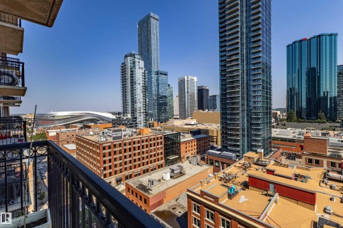 Private balcony with black metal railing overlooking a cityscape featuring various high-rise buildings and a prominent stadium in the distance - #1501 10180 104 St Nw, Edmonton, AB - Outdoor With Facade
