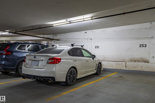 Underground parking space featuring concrete walls, overhead fluorescent lighting, painted parking space lines, and numbered parking stall identification - #1501 10180 104 St Nw, Edmonton, AB - Indoor Photo Showing Garage