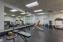 Dedicated fitness area featuring rubber flooring, extensive wall-mounted mirrors, recessed lighting, and a drop ceiling - 