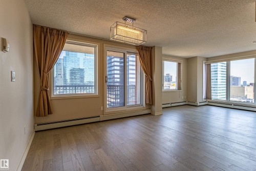 Spacious room with wood-finish flooring, multiple large windows, and a glass sliding door - #1501 10180 104 St Nw, Edmonton, AB - Indoor Photo Showing Other Room