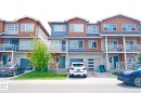 Modern townhome exterior featuring multi-toned siding, a private balcony with glass railings, an integrated garage, a paved driveway, and a covered entry - 17263 9 Avenue Sw, Edmonton, AB 