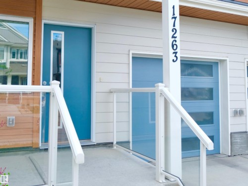 Modern exterior with light blue entry door featuring a vertical glass insert - 17263 9 Avenue Sw, Edmonton, AB 