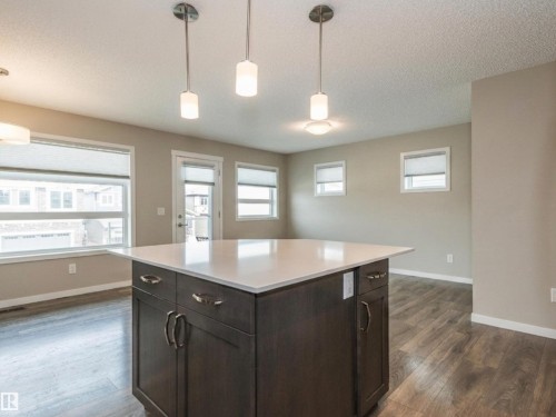 Kitchen island with a white countertop and dark wood-finish cabinetry - 17263 9 Avenue Sw, Edmonton, AB 