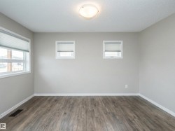 Neutral-toned living room featuring wood-finish flooring, white baseboards, and light gray walls - 