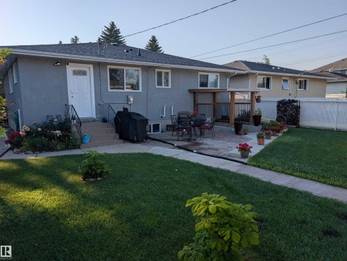 Spacious backyard featuring a large paved patio, manicured lawn, and a built-in wooden pergola structure - 13216 117 Street Nw, Edmonton, AB - Outdoor