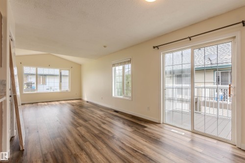 Spacious room featuring wood-finish flooring, a vaulted ceiling, and multiple windows - #D 10102 103 St, Morinville, AB - Indoor Photo Showing Other Room