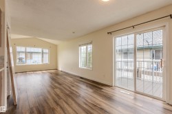 Spacious room featuring wood-finish flooring, a vaulted ceiling, and multiple windows - 