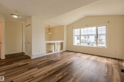 Spacious interior featuring wood-finish flooring, a vaulted ceiling, and a large multi-pane window - 