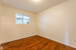 Room featuring wood-finish flooring, white baseboards, a white-framed window, neutral painted walls, and a textured ceiling - 
