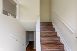 Staircase featuring wood-finish treads, white risers, and coordinating white handrails - 