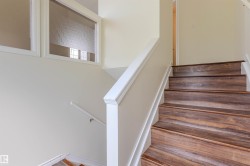 Staircase featuring wood-finish treads, white risers, and a prominent white newel post - 