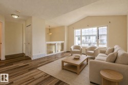 Living area featuring wood-finish flooring, vaulted ceiling, large windows, and a partial glass panel wall - 