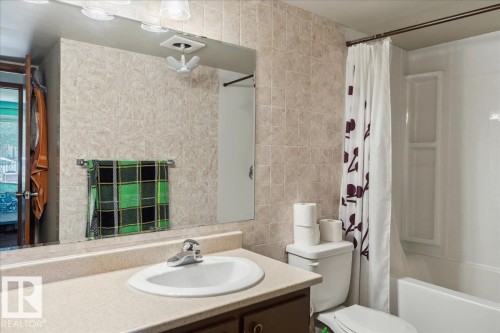Bathroom vanity with an integrated sink, laminate countertop, and wood-finish cabinetry - #112 2904 139 Av Nw, Edmonton, AB - Indoor Photo Showing Bathroom