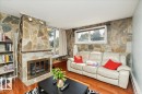 Living area featuring a stone fireplace with a metal insert, track lighting, and built-in shelving - #112 2904 139 Av Nw, Edmonton, AB  - Indoor Photo Showing Living Room With Fireplace 