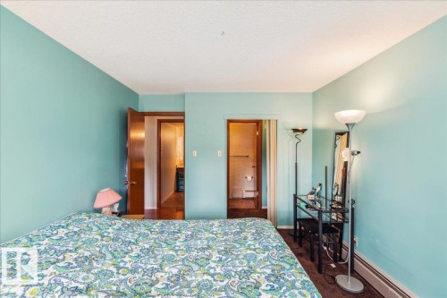 Bedroom featuring light blue walls, dark wood-finish flooring, white baseboard heating, and two internal doorways - #112 2904 139 Av Nw, Edmonton, AB - Indoor Photo Showing Bedroom
