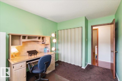 Carpeted room featuring a built-in closet with accordion-style doors and a solid wood door frame - #112 2904 139 Av Nw, Edmonton, AB - Indoor Photo Showing Office
