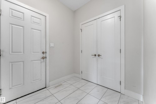 Entryway featuring durable large-format tile flooring, a paneled entry door, and a double-door closet with contemporary hardware - 3001 55 Street, Beaumont, AB - Indoor Photo Showing Other Room