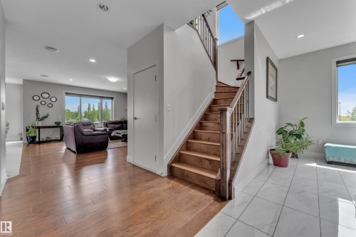Foyer featuring white tile flooring and a hardwood staircase with a wood railing - 3001 55 Street, Beaumont, AB - Indoor