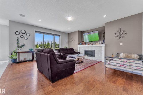 Expansive living area featuring wood-finish flooring, recessed lighting, and a large window - 3001 55 Street, Beaumont, AB - Indoor Photo Showing Living Room With Fireplace