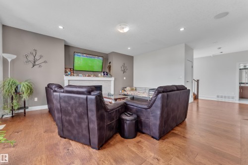 Living area featuring wood-finish flooring, a white mantel, and recessed lighting - 3001 55 Street, Beaumont, AB - Indoor With Fireplace