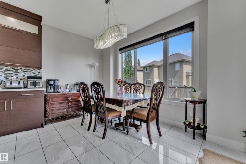 Dining area featuring a large window, tile flooring, and a contemporary chandelier - 3001 55 Street, Beaumont, AB - Indoor Photo Showing Dining Room