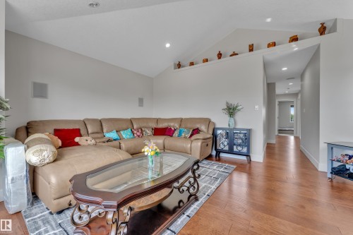 Living area featuring vaulted ceilings, recessed lighting, wood-finish flooring, a decorative wall shelf, and built-in speakers - 3001 55 Street, Beaumont, AB - Indoor Photo Showing Living Room