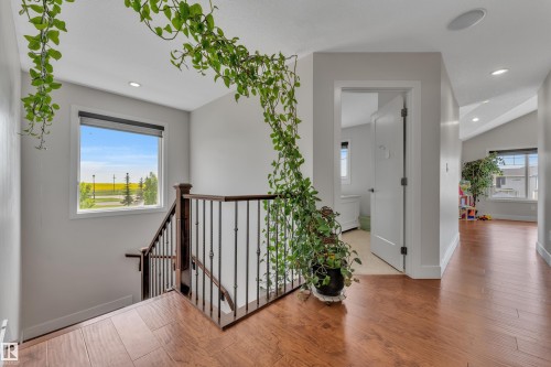Upper-level landing featuring rich wood-finish flooring, a contemporary staircase with dark wood handrails and wrought iron balusters, and recessed lighting - 3001 55 Street, Beaumont, AB - Indoor Photo Showing Other Room