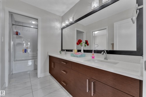 Bathroom featuring a double vanity with wood-finish cabinetry, white countertops, and dual undermount sinks - 3001 55 Street, Beaumont, AB - Indoor Photo Showing Bathroom