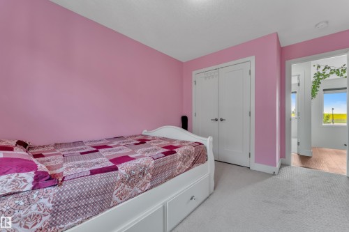 Bedroom featuring light-colored carpet flooring and a double-door closet with brushed nickel hardware - 3001 55 Street, Beaumont, AB - Indoor Photo Showing Bedroom