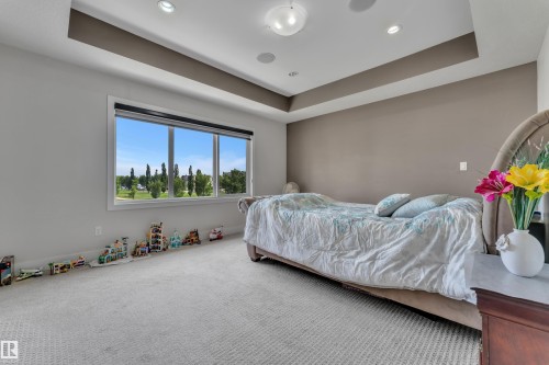 Bedroom featuring a large three-panel window, tray ceiling, recessed lighting, and neutral carpeting - 3001 55 Street, Beaumont, AB - Indoor Photo Showing Bedroom