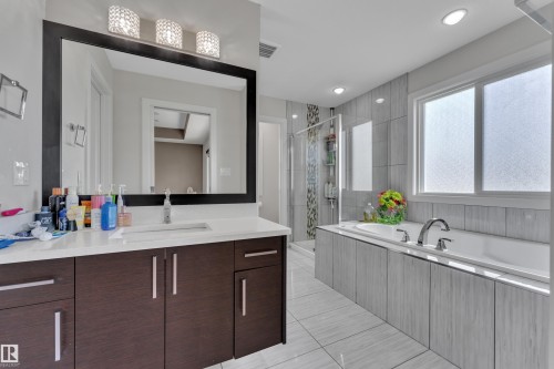 Contemporary bathroom featuring a dark wood-finish vanity with an integrated rectangular sink, a large framed mirror, and a three-light vanity fixture - 3001 55 Street, Beaumont, AB - Indoor Photo Showing Bathroom