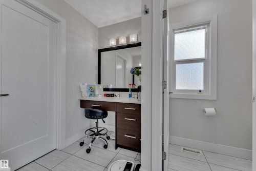 Vanity area featuring a dark wood-finish cabinet with multiple drawers, a light-toned countertop, and a large framed mirror - 3001 55 Street, Beaumont, AB - Indoor Photo Showing Bathroom