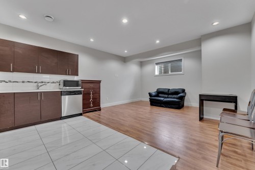 Open concept living area featuring a compact kitchen with dark wood-finish cabinetry, stainless steel appliances, and a white subway tile backsplash - 3001 55 Street, Beaumont, AB - Indoor
